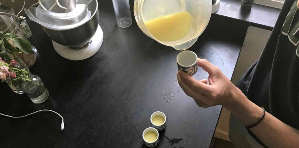 Person pouring a ginger shot because there are a variety of benefits of ginger shots.