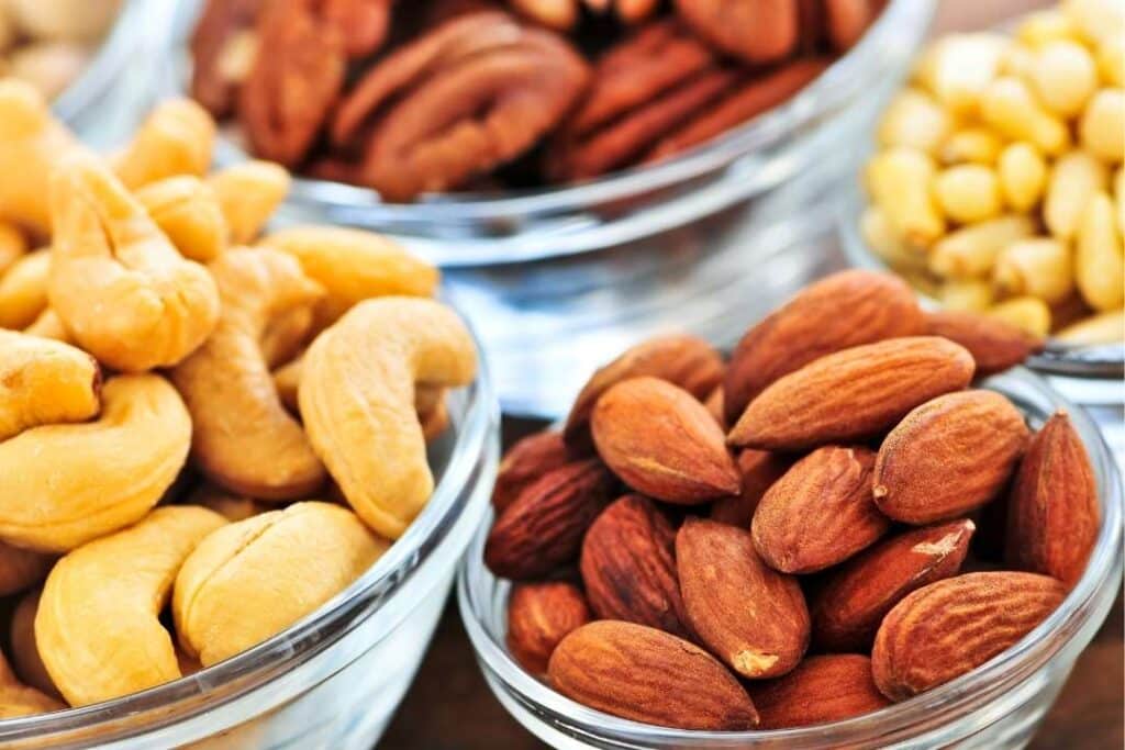 Bowls of almonds, cashews, and pecans which are high protein nut sources. 