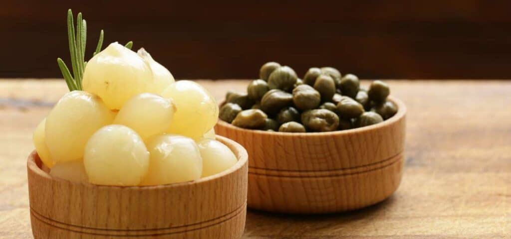 Bowls of onions and capers which are quercetin-rich foods.