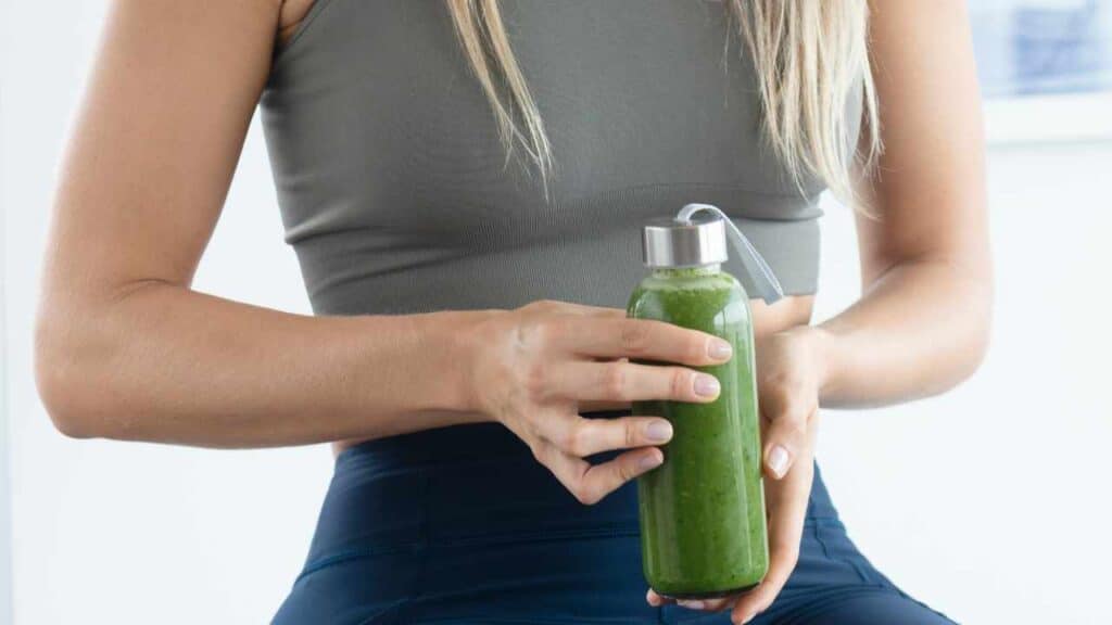 Girl holding a green smoothie concerned about gut health and wondering do greens powders help with going poop?