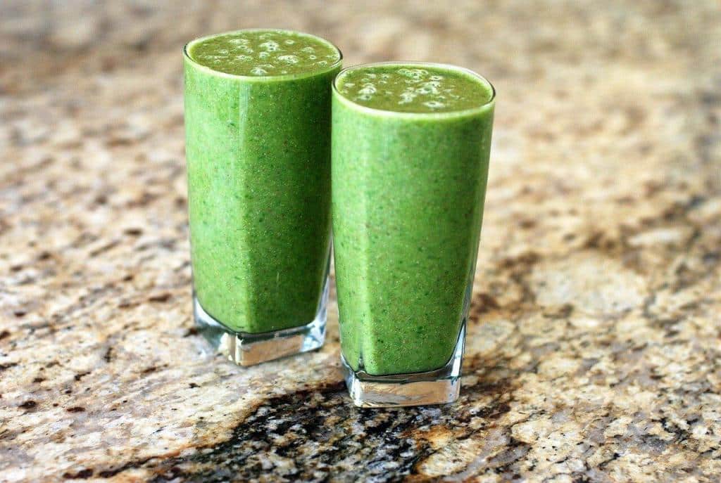 Two green elimination diet breakfast smoothie glasses sitting on a counter