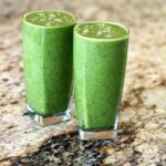 two green elimination diet breakfast smoothie glasses sitting on a counter