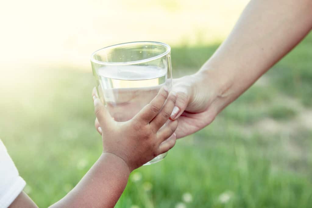 Woman handing a child a glass of water