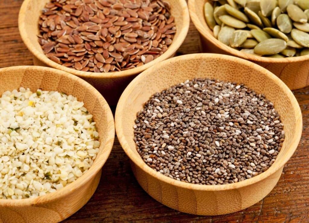 Bowls of hemp, chia, flax, and almonds to demonstrate the seeds and the best nuts for athletes