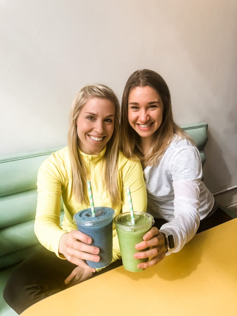 Two dietitians holding cups and showing how to make your own protein shake.