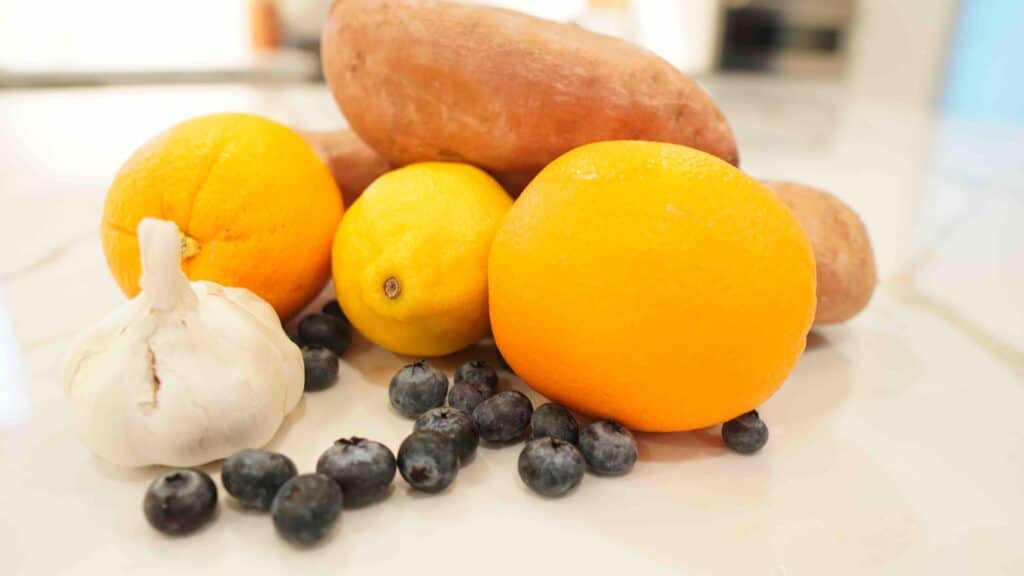 Mycotoxin detox diet foods examples including sweet potatoes, blueberries, garlic, and citrus fruits. 