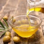 Pouring olive oil which can help reduce inflammation in the body. 